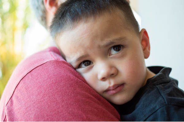 Toddler leaning head on adult shoulder